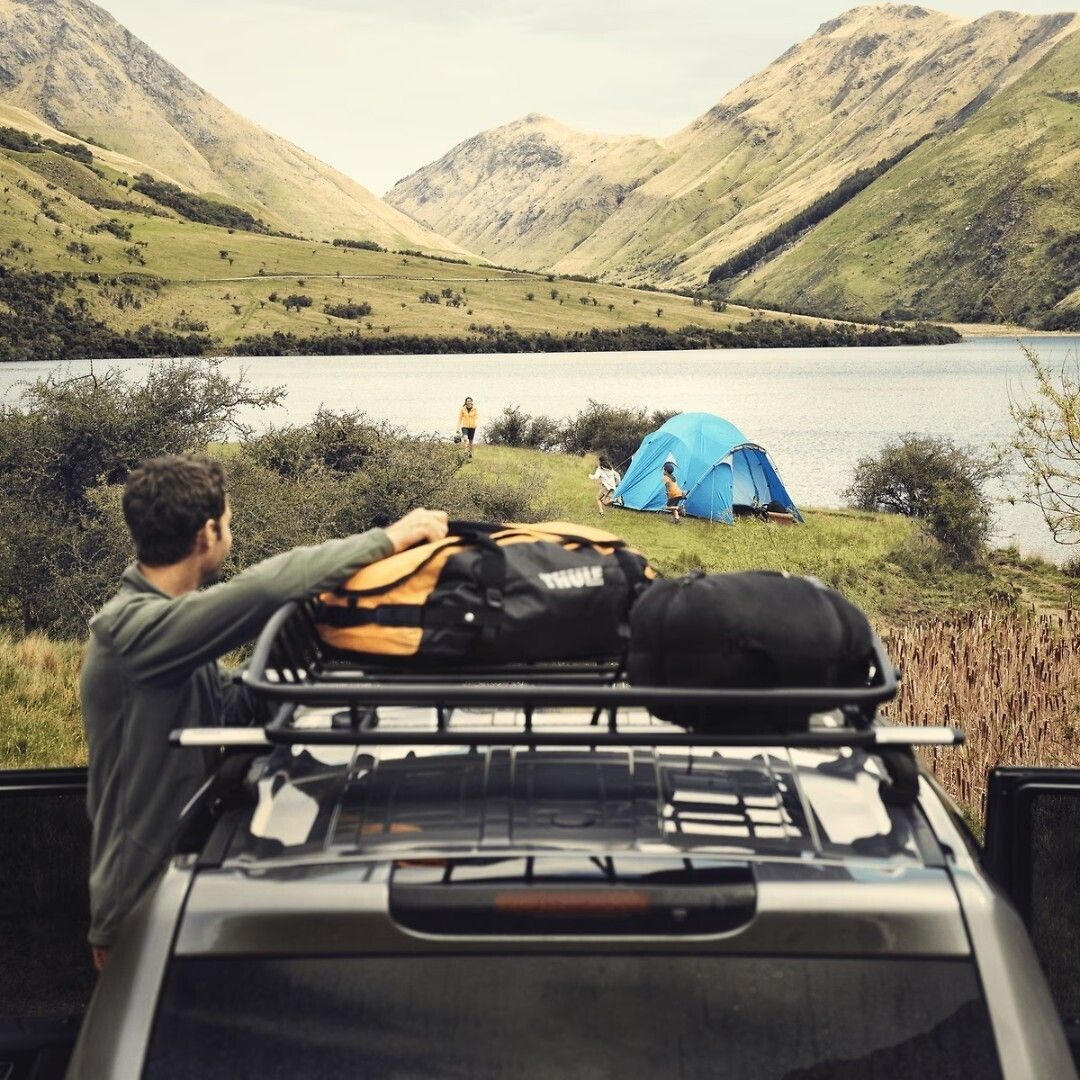 Luggage in a roof mounted cargo basket near a tent