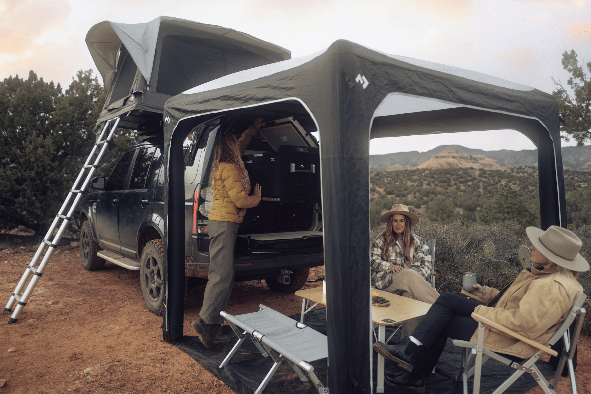 A camping setup with a rooftop tent and camping chairs and tables