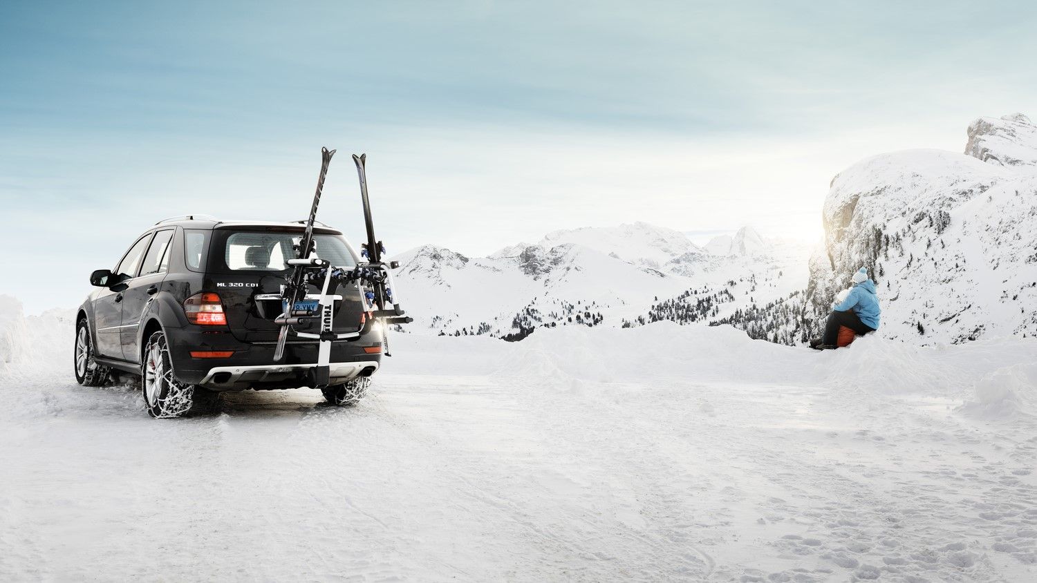 A car carrying skis on a hitch-mounted carrier in the mountains