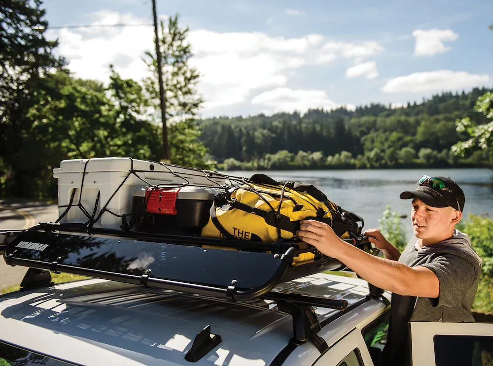 camping gear being stowed in a roof mounted cargo basket