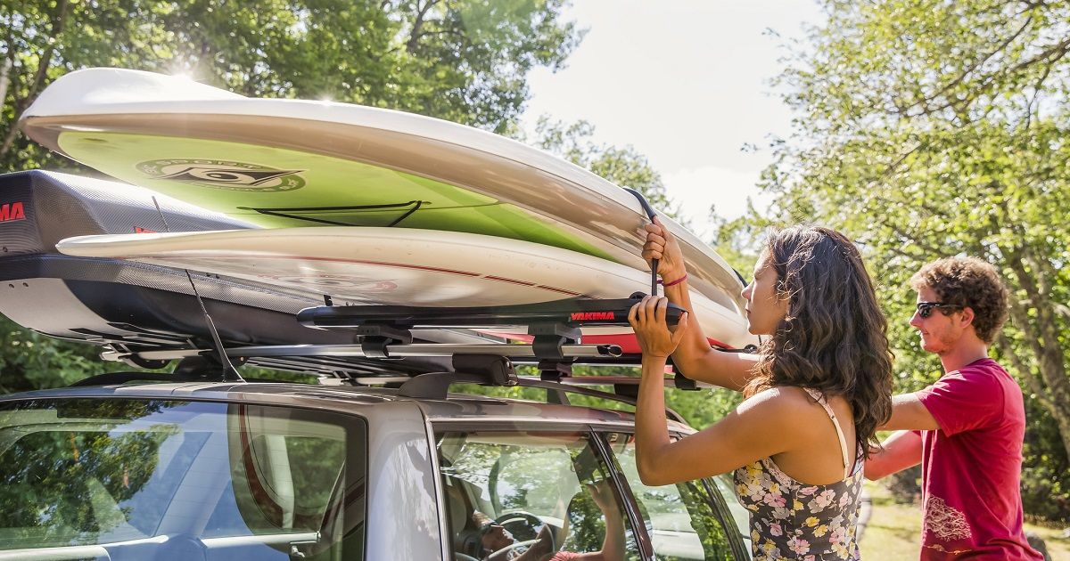 A car with paddleboards being loaded on top