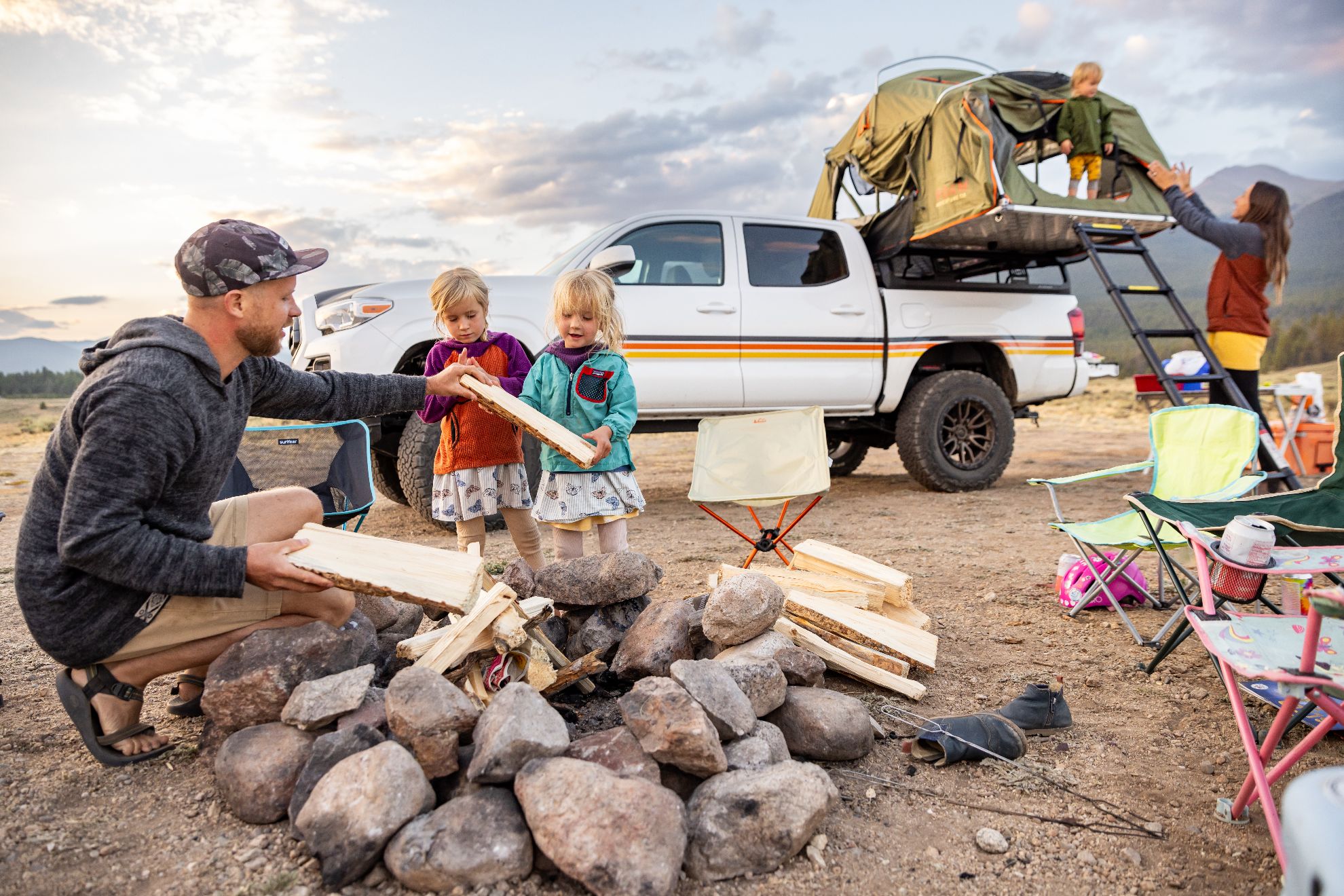 A campfire and truck with a roof top tent for 4 people